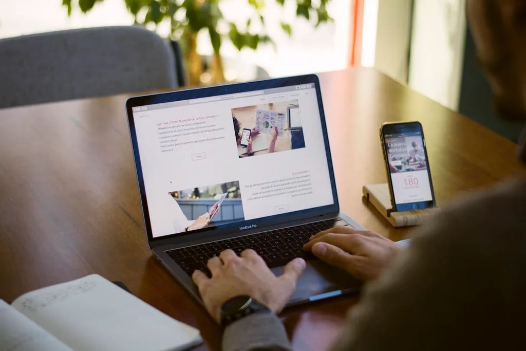 Notebook e celular usados lado a lado numa mesa de trabalho