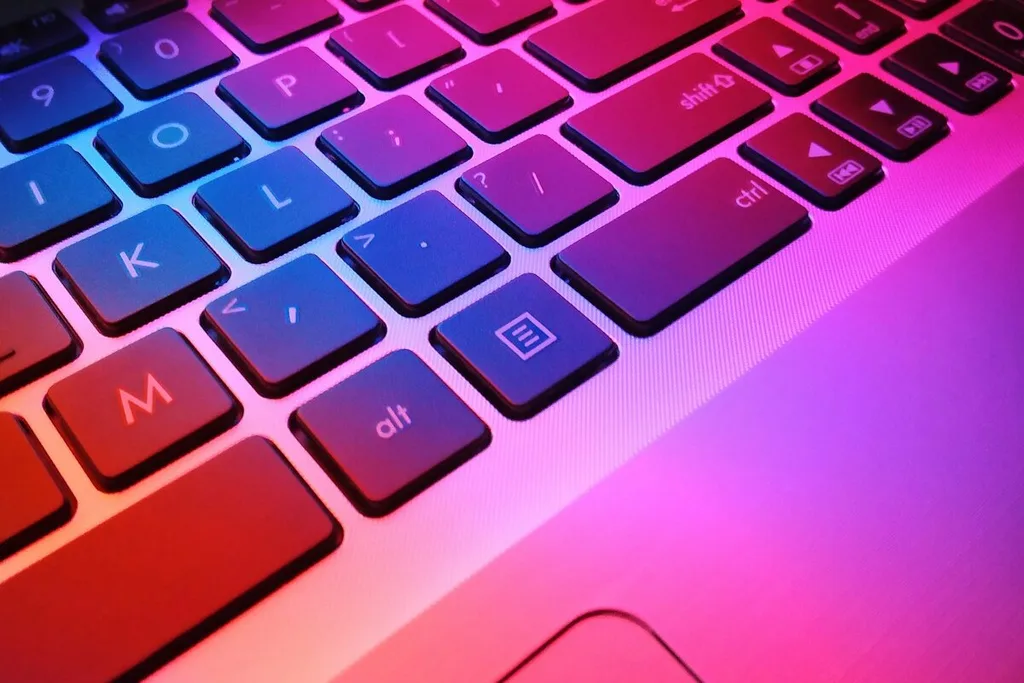 Teclado de notebook iluminado em azul e rosa.