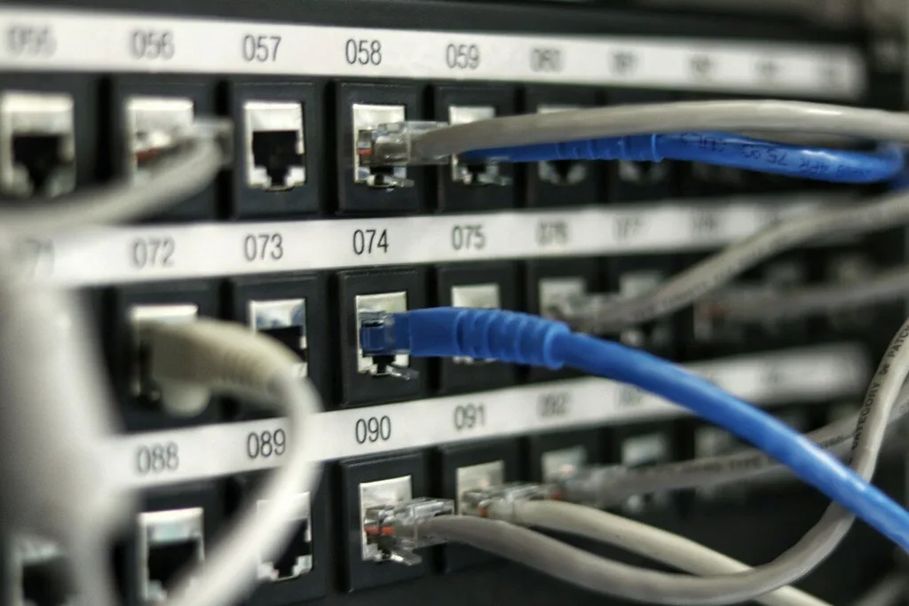 Cabos de rede azuis e cinza conectados a portas numeradas de um patch panel